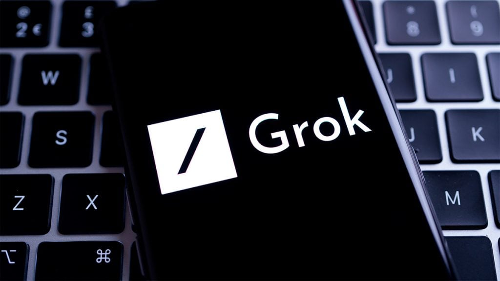 Celular com logotipo do Grok sobre teclado de Mac