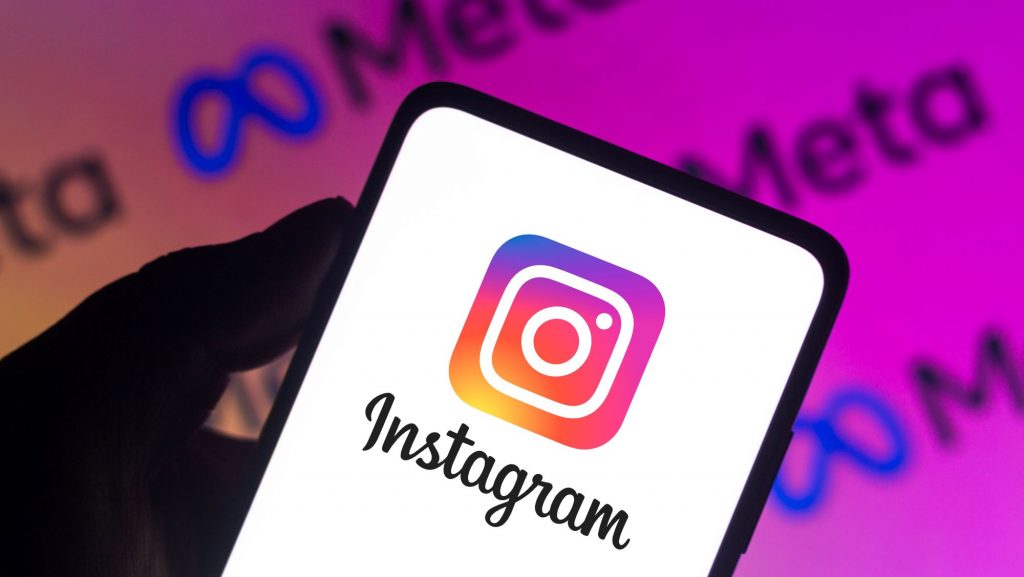 Logo da Meta no fundo; à frente, logo do Instagram em um smartphone