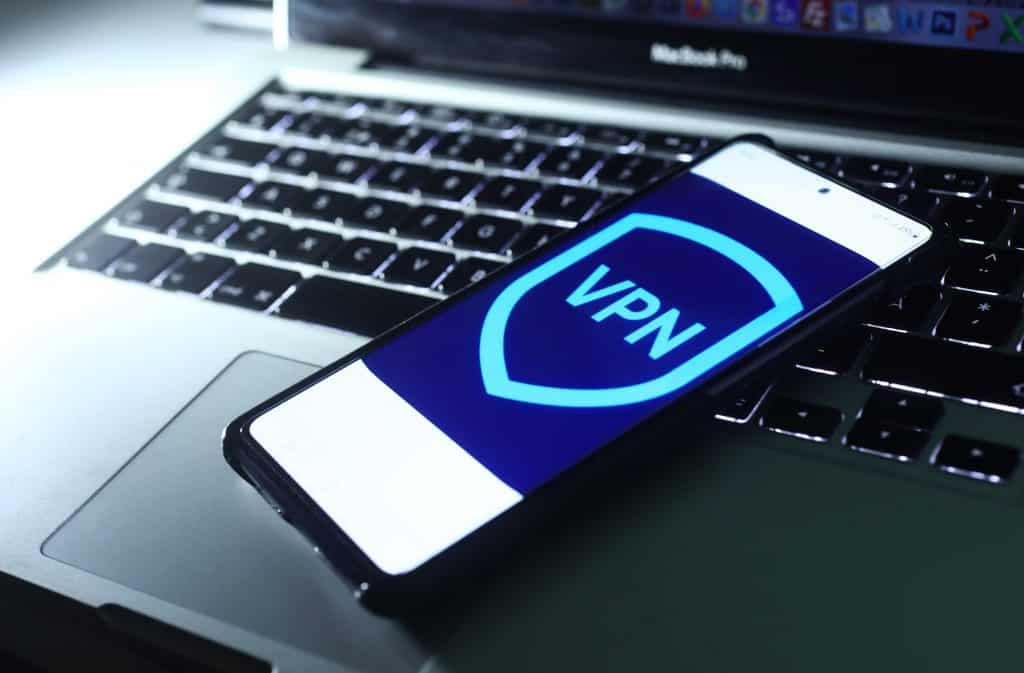 Imagem de um logo de VPN em um smartphone, que está em cima de um notebook